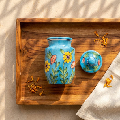 Jaipur Blue Pottery storage jar with lid removed on a dark tray, turquoise and yellow sunflower motif visible