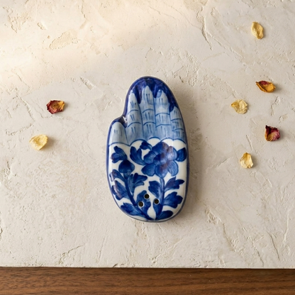 Blue Pottery Hamsa-shaped incense stand with hand-painted white floral motif on cobalt, unlit, full form