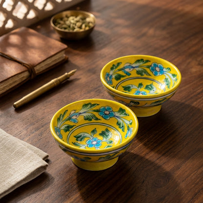 Pair of handcrafted yellow Jaipur Blue Pottery bowls with blue floral and green vine motifs styled on a wooden table