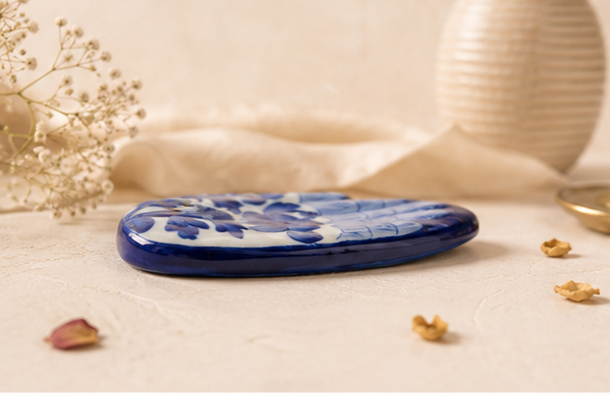 Profile view of a Jaipur Blue Pottery hand incense holder showing flat oval palm form and painted surface