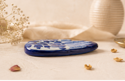 Profile view of a Jaipur Blue Pottery hand incense holder showing flat oval palm form and painted surface